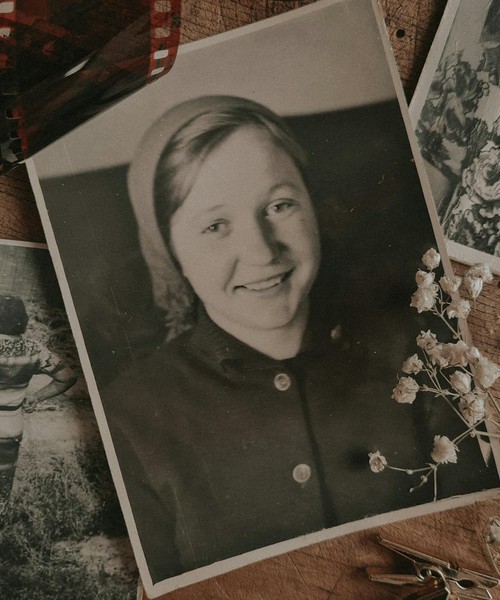 An arrangement of vintage family photos with dried flowers and film negatives, evoking nostalgia.